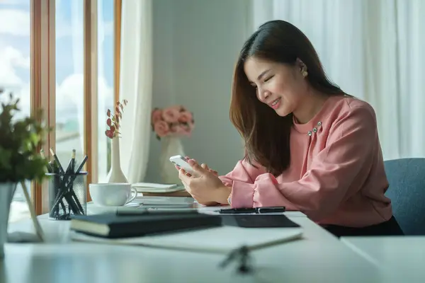 Smiling Female Employee Sitting Bright Office Using Smart Phone Communicating — ストック写真