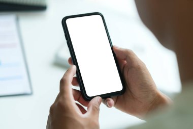 Çalışma yerinde oturan ve akıllı telefon kullanan genç bir adamın dikiz görüşü. Grafik görüntüleme kurgusu için boş ekran.
