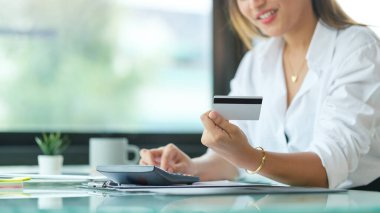 Elinde kredi kartı tutan mutlu bir kadın. Çevrimiçi alışveriş, e-ticaret kavramı.