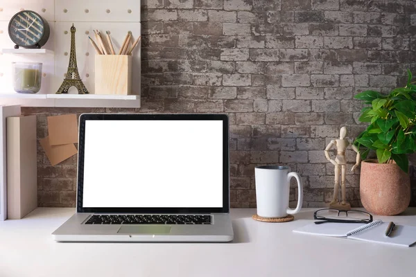 Laptop, kahve fincanı, ev bitkileri ve kırtasiye malzemesi olan şık bir iş yeri..