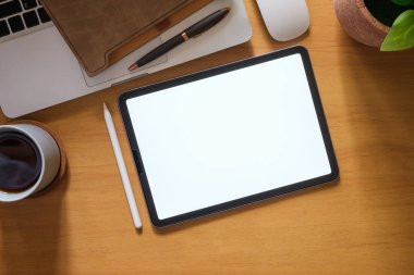 Top view of digital tablet, glasses, coffee cup and notebook on wooden table. Blank screen for advertise text.	