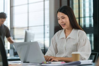 Beautiful businesswoman working with laptop computer in bright office.	