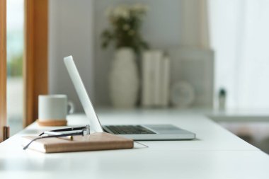 Laptop gözlüklü, mali belgeleri ve kalem tutacağı olan modern işyeri.