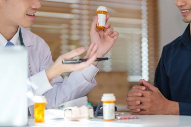 Beyaz önlüklü doktor hastaya ilaç dozajını açıklıyor..