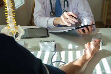 Ortopedist dijital tableti işaret ediyor, tedavi kursunu açıklıyor, erkek hastaya iyileşme tavsiyesi veriyor. Tıbbi, ortopedik ve sağlık hizmetleri kavramı.