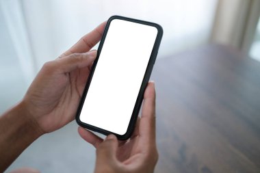 Boş ekranlı dizüstü bilgisayar, saksı bitkisi, resim çerçevesi ve beyaz masadaki kırtasiye malzemesi.