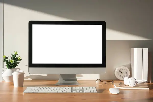 フロントビューの空白のコンピュータ デスクトップおよび木のテーブルのオフィスの供給 広告のための空のスクリーン ストック画像