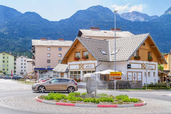 Bohinjska Bistrica, Slovenya - 19 Ağustos 2018: Şehir merkezinde bazı binalar ve bir döner kavşak, arkasında Crna Prst dağları, güneşli bir yaz gününde.