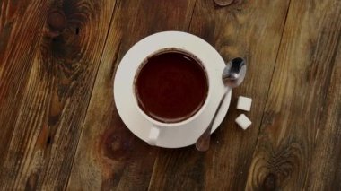 Çay kaşığıyla çay tabağının üzerinde sade kahve ve koyu ahşap masa üzerinde çekiliş şekeri. Üst görüntü, kopyalama alanı, yavaş çekim. Kapat..