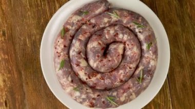 Çiğ domuz sucuğu çemberi ya da ızgara hazırlamak için domuz sucuğu yavaşça döner. Lezzetli et yemeği. Üst Manzara. Kapat..