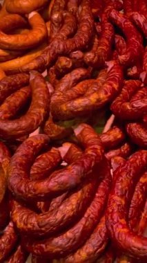 Pek çok tütsülenmiş sosis türü süpermarket tezgahındaki vitrin tipi buzdolabında satılıktır. Market vitrininde. Dikey. Kapat..