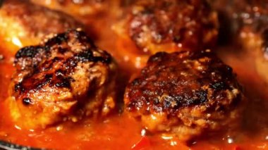 Meatballs with boiling tomato sauce in frying pan preparation tasty food. Cooking on domestic kitchen. Selective focus. Close up.