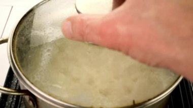 Boiling round rice in metal pot prepare healthy nutritious side dish. Preparation vegan or vegetarian healthy food. Slow motion. Close-up.