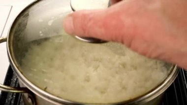 Boiling round rice in metal pot prepare healthy nutritious side dish. Preparation vegan or vegetarian healthy food. Slow motion. Close-up.