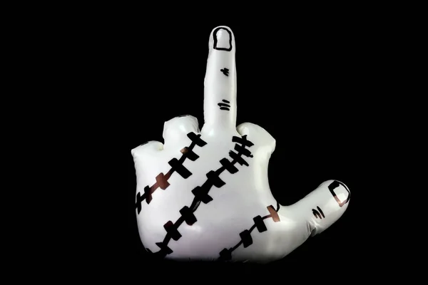 White sculpture in shape of hand showing obscene gesture against black background. Object of modern abstract art. Close-up.