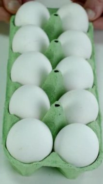 Chefs hand take white chicken eggs from cardboard eggs tray for cooking breakfast. Homemade cooking. Vertical. Close-up.