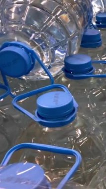 Bir sıra maden suyu şeffaf plastik şişelerde süpermarkette paketlenir. Büyük bir deponun bakkal bölümünde temiz içme suyu toptan satılıyor. Dikey. Kapat..