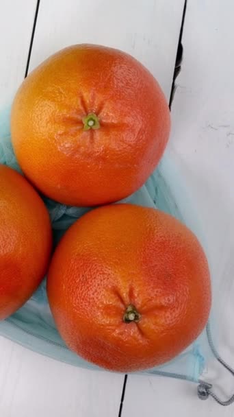 三个成熟的多汁柚子在生态友好型网格中在白色背景上旋转 柑橘类新鲜水果健康素食和素食 靠近点 — 图库视频影像