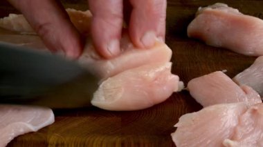 Çiğ tavuk göğsü yumuşak doku ve sulu görünüş ile dilimleniyor. Lezzetli yemekler pişirmek için taze tavuk göğsünü mutfak bıçağıyla kesiyorum. Kapat..