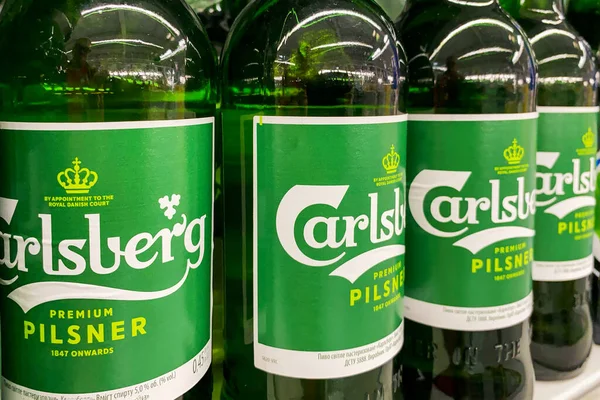 Kyiv, Ukrayna 28.07.2023: - Carlsberg bira markası süpermarkette raflarda cam şişeler halinde duruyor. Alkol bölümünde bir sürü bira şişesi var..