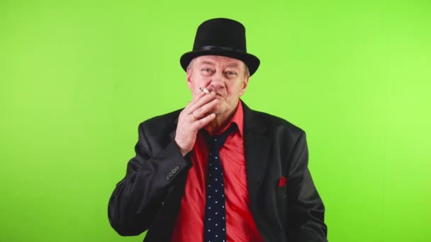 オールドファッションの残忍な成熟した男はタバコを吸って 帽子に敬意を表します 高齢の男性は挨拶で帽子を持ち上げ タバコを吸い 煙を吹き飛ばした クロマキー グリーンスクリーン — ストック動画