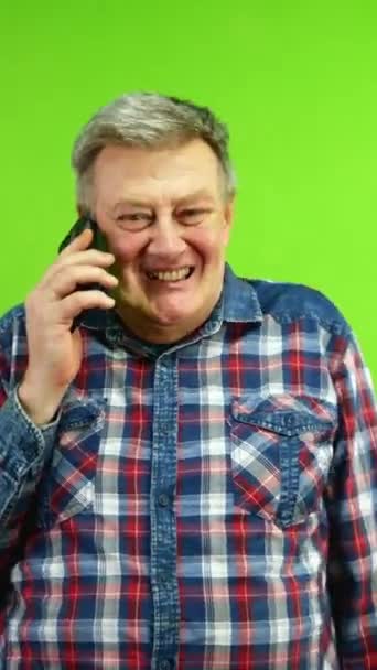 携帯電話で話し おかしな冗談でヒステリックに笑う年配の男性 スマートフォンとの楽しい会話をする成熟した人 グリーンスクリーン クロマキー バーティカル — ストック動画