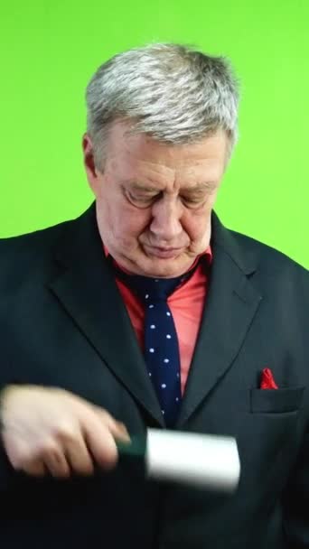 穿着老式西服的老人 用胶水滚筒擦拭衣服 对外表 服装优雅的关怀 绿色屏幕 垂直方向 — 图库视频影像