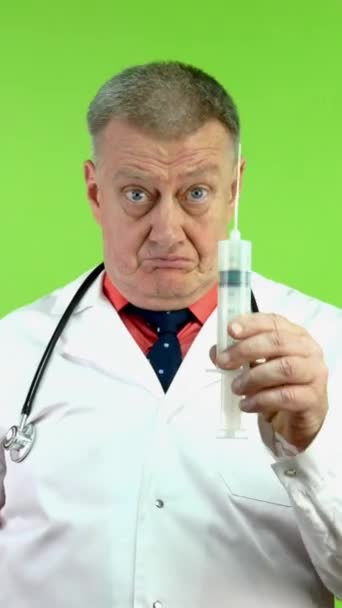 분노의 의사는 자신의 손가락과 주사기를 위협합니다 성숙한 의사는 행동에 실망하고 — 비디오