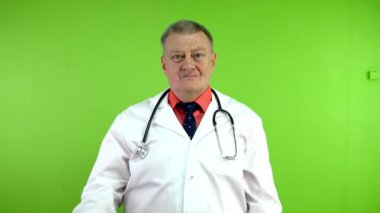 Sağlık hizmetlerine hazır kıdemli doktor kollarını kavuşturup kameraya gülümsedi. Uzman sağlık çalışanı gülümsüyor ve çalışmalarının sonuçlarından memnun. Yeşil ekran, krom anahtar.