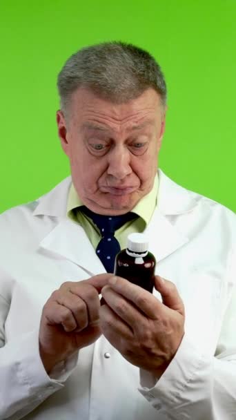 上級医師は 医薬品の指示を読み 患者に勧めない 薬瓶を持っている医療相談で成熟した医師アドバイス グリーン スクリーン クロマキー バーティカル — ストック動画