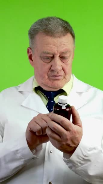 上級医師は医薬品の指示を読み 患者に勧める 薬瓶を持っている医療相談で成熟した医師アドバイス グリーン スクリーン クロマキー バーティカル — ストック動画