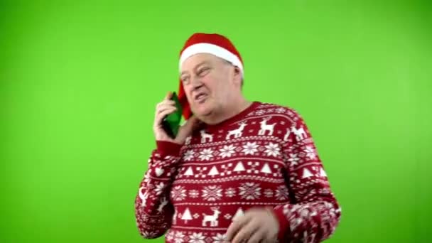 모자와 Xmas 스웨터에 전화로 성숙한 사람은 즐거운 크리스마스를 축하합니다 스크린 — 비디오