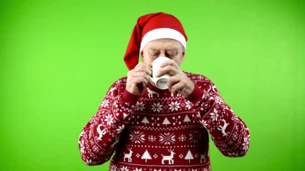 찻잔에서 마시는 모자와 Xmas 스웨터에 아늑한 성숙한 사람은 뜨거운 초콜릿을 — 비디오