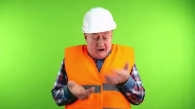 Sert şapkalı kızgın kıdemli müteahhit ellerini sallıyor, bağırıyor ve yüksek sesle küfrediyor. Olgun işçi kollarını sallıyor ve öfkeyle bağırıyor. Yeşil ekran, krom anahtar.