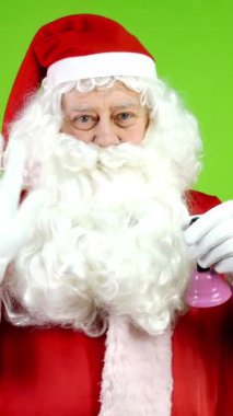 Kırmızı elbiseli neşeli Noel Baba Noel çanı çalıyor ve elini sallıyor. Neşeli Noel Baba Noel 'in gelişinde neşeli duyurular yapar. Sesle. Yeşil ekran. Krom Anahtar. Dikey.