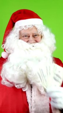 Otantik neşeli Noel Baba dolar kazanıp işaret parmağıyla gösteriyor. Noel zamanı kırmızı takım elbiseli neşeli Noel Baba. Yeşil ekran. Krom Anahtar. Dikey.