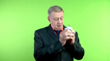 Kıdemli adam bozuk çalar saati sallar ve tamir etmek için çalar. Olgun kişi saati tamir etmeye çalışıyor ve başardığında çok memnun oluyor. Yeşil ekran, krom anahtar.
