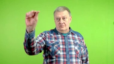 Kıdemli adam kameraya bakıyor, parmağını şıklatıyor ve birine el hareketi yapıyor. Olgun insan el işaretleri yapar ve birinin ona geldiğini işaret ederek ellerini sallar. Yeşil ekran, krom anahtar.
