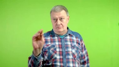 Kıdemli adam kameraya bakıyor, parmağını şıklatıyor ve birine el hareketi yapıyor. Olgun insan el işaretleri yapar ve birinin ona geldiğini işaret ederek ellerini sallar. Yeşil ekran, krom anahtar.