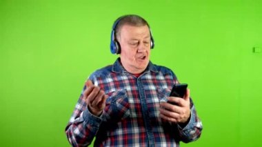 Kablosuz kulaklıklı son sınıf öğrencisi cep telefonuyla görüntülü konuşma yapıyor. Akıllı telefonu olan olgun bir insan. Bu da bunu kendi elleriyle işaret ederek açıklıyor. Yeşil ekran, krom anahtar.