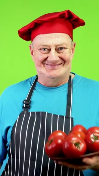穿着围裙的老厨师用手指着一堆西红柿 表示赞成健康的生活方式 指成熟的西红柿 厨师为素食主义或素食做广告 绿色屏幕 — 图库视频影像