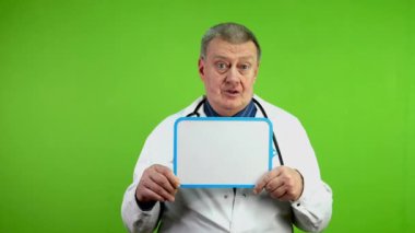 Beyaz önlüklü kıdemli doktor konuşuyor ve beyaz perdeli masayı işaret ediyor. Uzman sağlık çalışanları danışmanlık yapar ya da tıbbi sunum yapar. Yeşil ekran, krom anahtar.