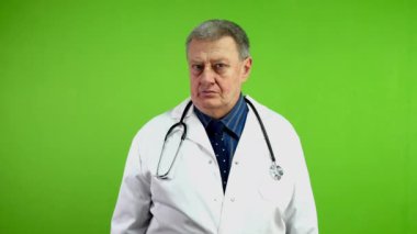 Beyaz önlüklü kıdemli doktor ne yazık ki olumsuz muayene sonuçları gösteriyor. Pratisyen terapist kafasını eğiyor ve ellerini empati ile açıyor. Yeşil ekran, krom anahtar.