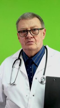 Beyaz önlüklü kıdemli gülümseyen doktor elinde dosyayla yürüyor. Olgun sıhhiyeci enerjiyle buluşmaya ya da hastaları görmeye gider. Yeşil ekran. Krom anahtar. Dikey.