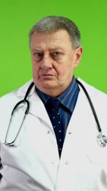 Beyaz önlüklü kıdemli doktor ne yazık ki olumsuz muayene sonuçları gösteriyor. Pratisyen terapist kafasını eğiyor ve ellerini empati ile açıyor. Yeşil ekran, krom anahtar. Dikey.