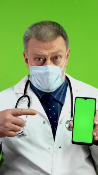 Läkare Medicinsk Mask Håller Telefonen Med Grön Skärm Och Pekar — Stockvideo
