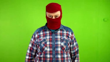 Maskeli tehlikeli bir suçlu bıçakla tehdit ediyor, birini yumrukluyor. Haydut soğuk çeliği tehditkar bir şekilde sallıyor ve yumruğunu gösteriyor. Yeşil ekran. Krom anahtar.