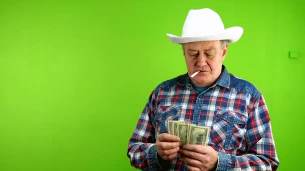 Ηλικιωμένος Άσπρο Καουμπόικο Καπέλο Βγάζει Δολάρια Καπνίζει Τσιγάρο Και Φυσάει — Αρχείο Βίντεο