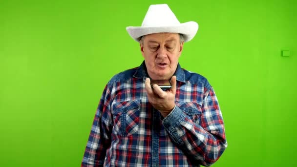 Pria Senior Bertopi Koboi Putih Merekam Pesan Suara Dengan Speakerphone — Stok Video
