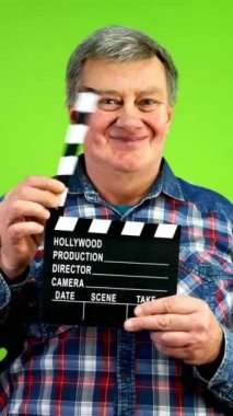 Film çekimi sırasında arkadaş canlısı, eğlenceli kıdemli adam alkışlıyor. Olgun film ekibi sinemada bir sahne daha açıyor. Yeşil ekran, krom anahtar. Dikey.